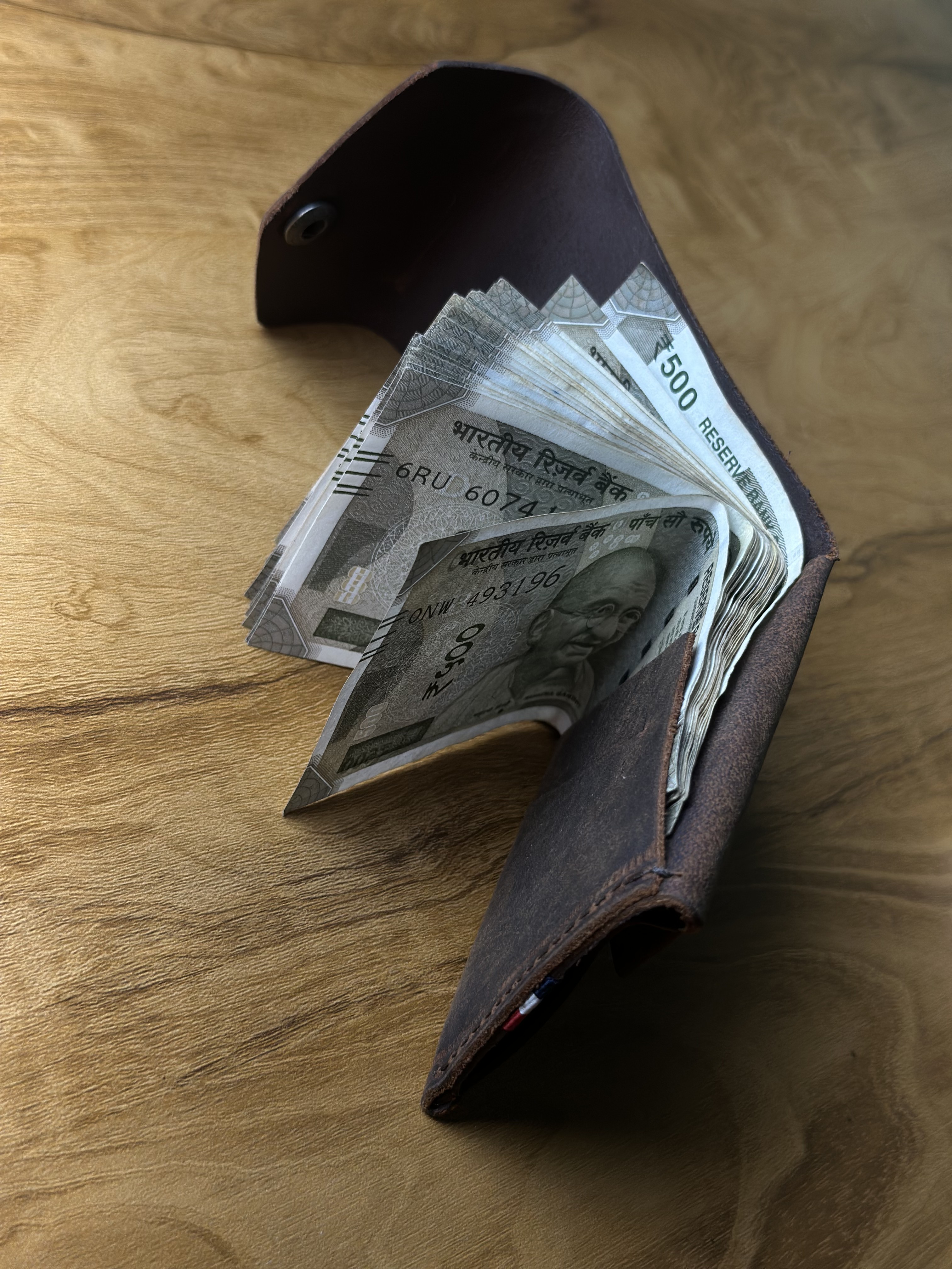 Wallet fanned with cash on wood